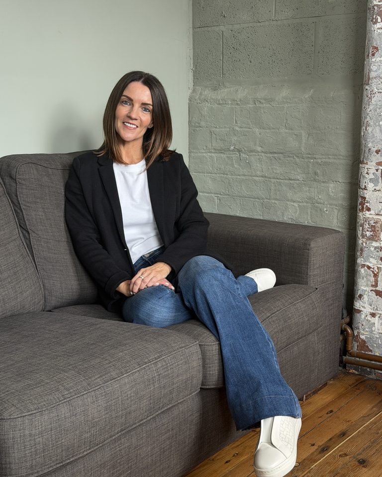 Chriselle Louise, founder of The Unrushed Mind, sitting on a sofa and smiling